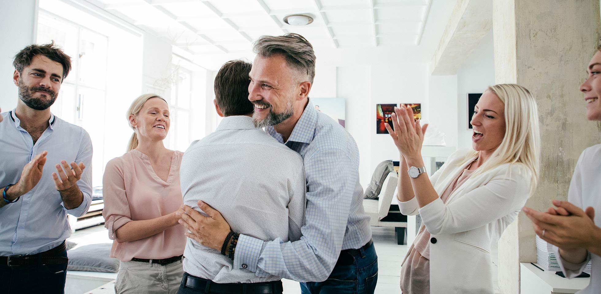 Une équipe de bureau fait la fête ensemble, s'embrasse et s'applaudit après une présentation commerciale réussie.