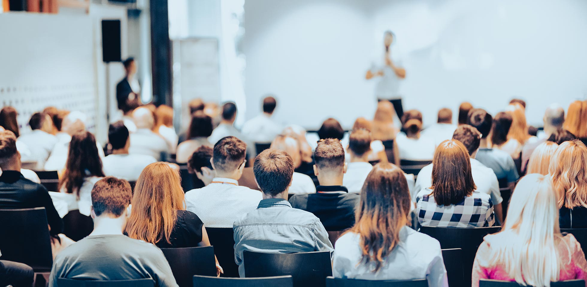 Conférencier donnant une conférence dans une salle de conférence lors d'un événement professionnel. Vue arrière de personnes non identifiables dans le public de la salle de conférence. Concept d'affaires et d'entrepreneuriat.